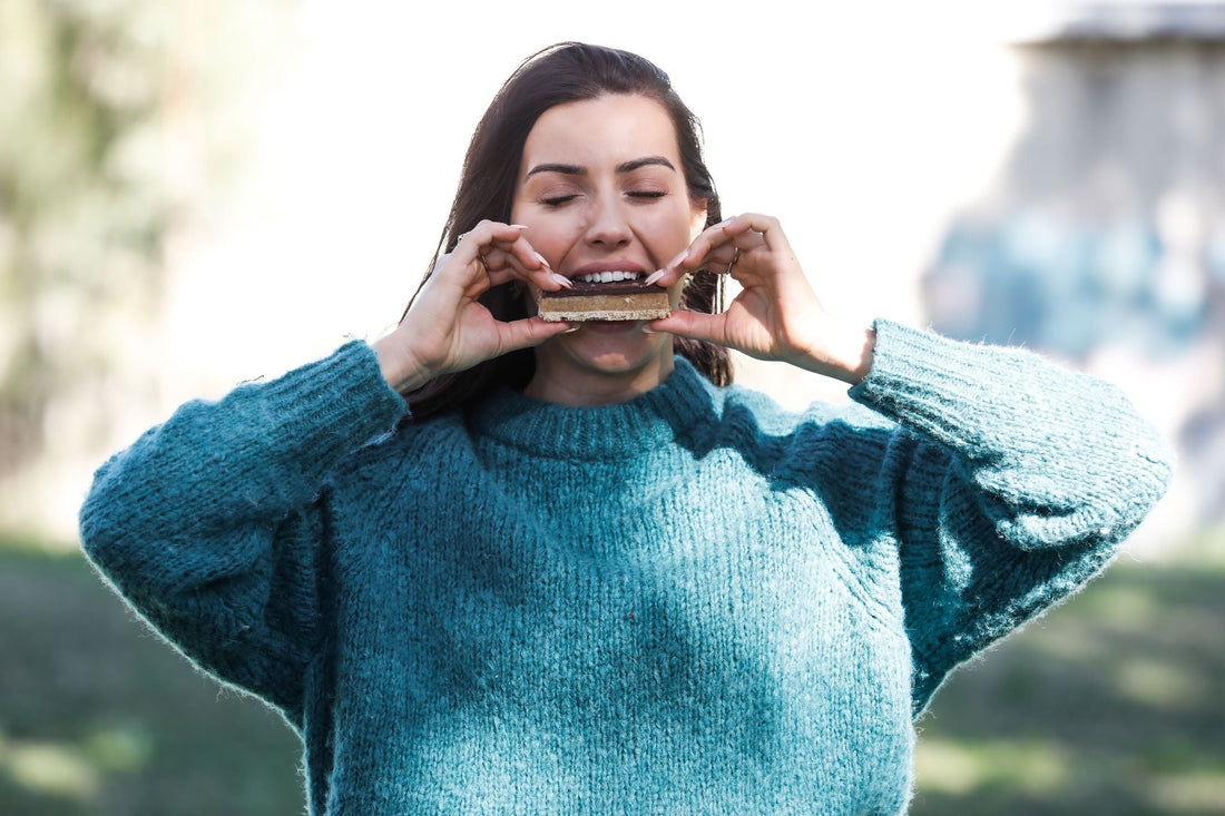 Woman eating a chocolate wagon wheel outdoors – Crumble Charms gluten-free vegan treat