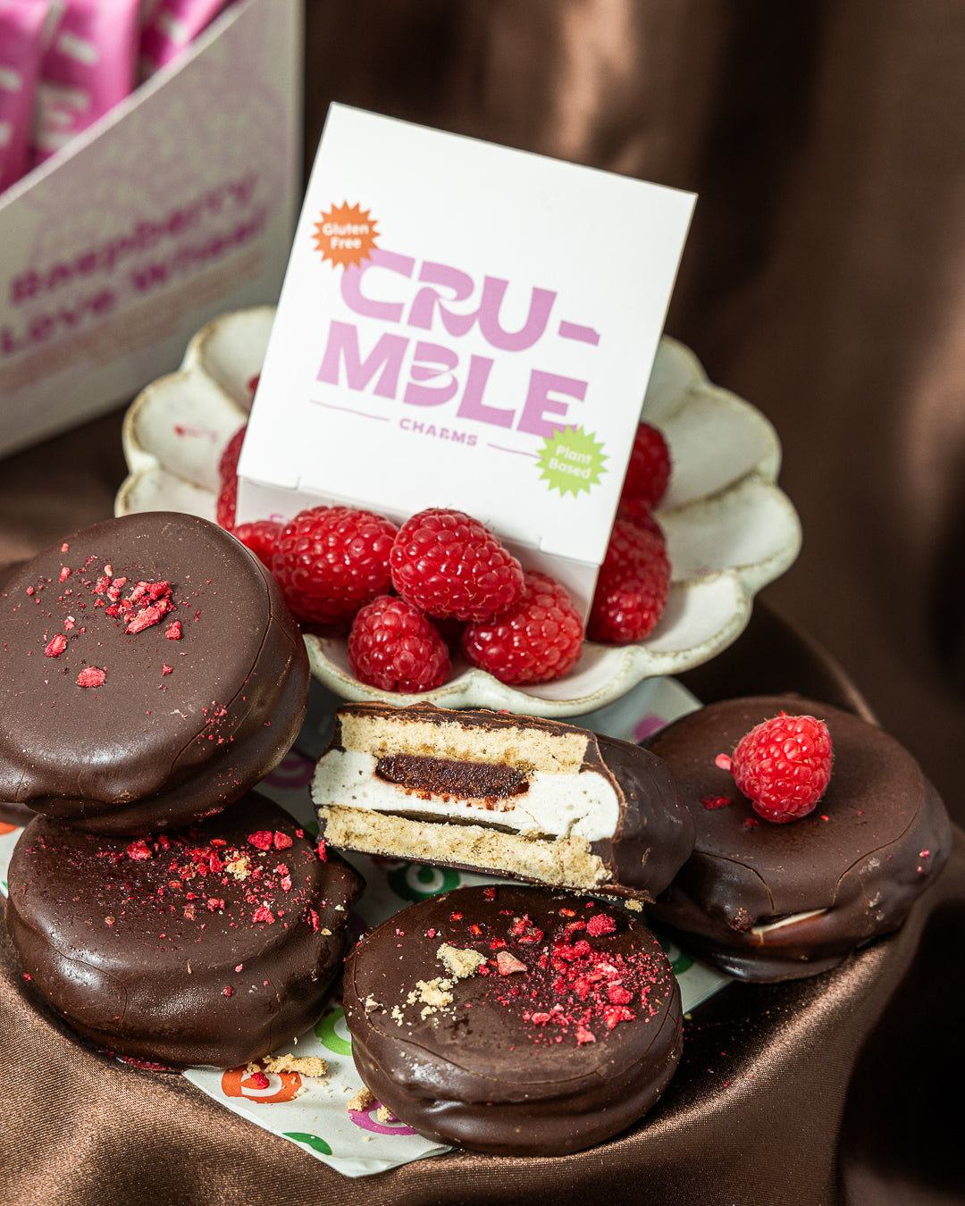 Chocolate-dipped cookies with raspberries and a 'Crumble' sign in the background